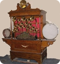 An ornate oak nickelodeon cabinet with rows of brass bells, a drum, and organ pipes